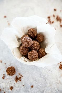 chocolate truffles in a paper bag on a white surface with brown flecks