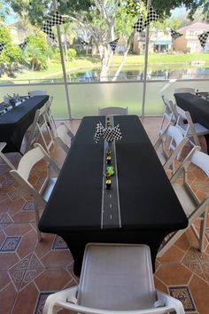 a long table set up with black tables and white chairs