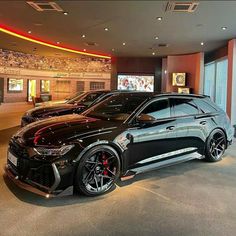 two black cars are parked in a showroom