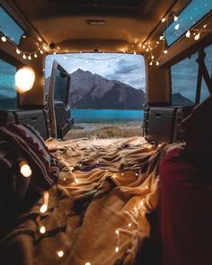 the inside of an rv with lights and blankets on the bed in front of it