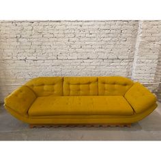 a large yellow couch sitting in front of a brick wall with white bricks on it