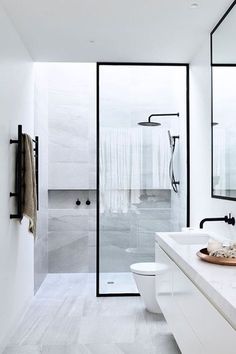 a white bathroom with two sinks and a large mirror on the wall next to it