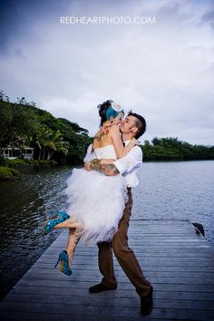 a man carrying a woman on his back while walking along a pier near the water