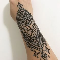 a woman's arm with a black and white tattoo design on the left side of her arm