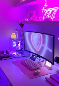 a desk with a computer monitor, keyboard and mouse in front of a neon sign