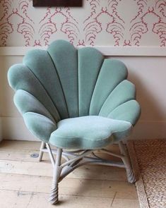 a blue shell chair sitting on top of a wooden floor next to a white wall