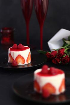 two desserts on black plates with red roses and wine glasses in the back ground