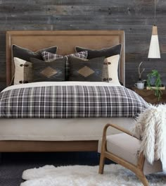 a bed with plaid sheets and pillows in a bedroom next to a wooden headboard