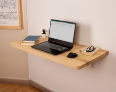 a laptop computer sitting on top of a wooden desk next to a mouse and book