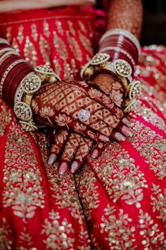 the bride's hands are decorated with gold and red jewelry