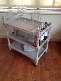 an old bar cart with wine glasses on it