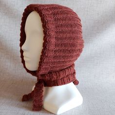 a crocheted hat on a mannequin head with a scarf around it