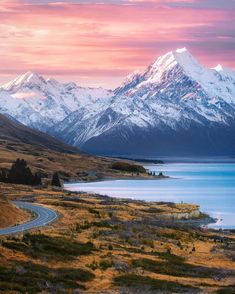 a scenic view of a mountain range with a road winding through it