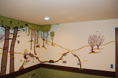 a child's room with a mural on the wall and trees painted on the walls