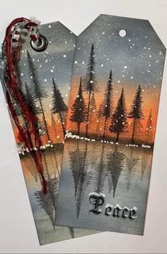 two tags with the words peace painted on them and trees in the snow at night