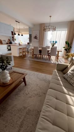 a living room filled with furniture next to a kitchen and dining room table on top of a hard wood floor