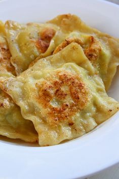 some food is in a white bowl on top of a table and it looks like dumplings