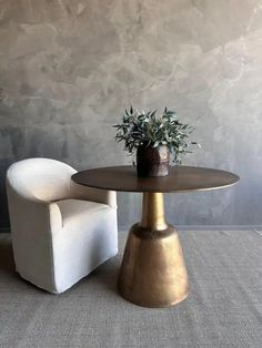 a white chair sitting next to a table with a potted plant on top of it