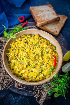 a bowl filled with yellow food next to bread