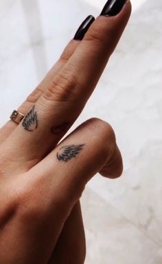 a woman's hand with a ring on it and a butterfly tattoo on the middle finger