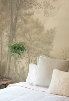 a bed with white sheets and pillows in front of a forest wallpapered bedroom