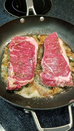 two steaks cooking in a frying pan on the stove