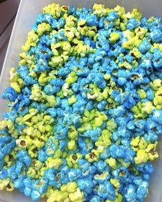 a plastic container filled with blue and green popcorn kernels on top of a table