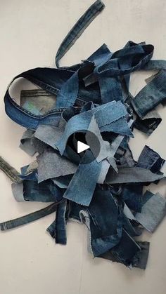 a pile of blue jeans sitting on top of a white table next to a pair of scissors