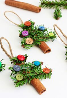 small christmas tree ornaments made out of cinnamon sticks and buttons on a white surface with twine of twine