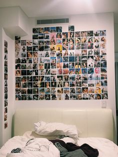 a white bed topped with lots of pictures next to a wall covered in photos and blankets