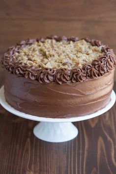 a chocolate cake sitting on top of a white plate next to a brown wooden table