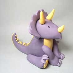 a purple toy with yellow horns and spikes on its head sits in front of a white background