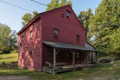 an old red barn with a porch and covered porch