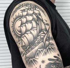 a man's arm with a black and white ship tattoo on the left sleeve