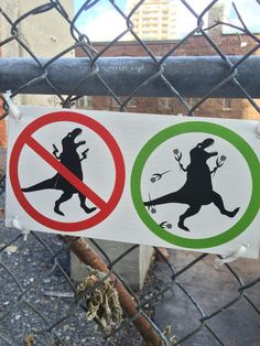 two signs on a chain link fence that say no dinosaurs