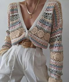 a woman wearing white pants and a crocheted sweater