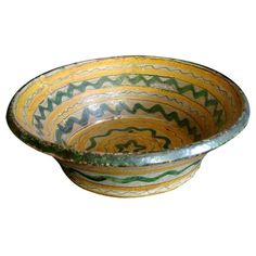 a bowl that is sitting on top of a white surface with green and yellow designs