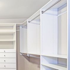 an empty closet with white shelves and drawers