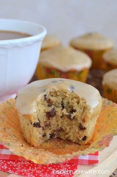 a cupcake with frosting and chocolate chips is on a plate next to some muffins