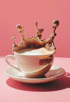 a white cup with liquid in it on a saucer against a pink background that is shaped like a crown