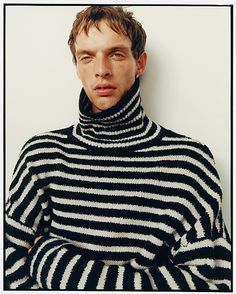 a young man wearing a black and white striped sweater with his hands on his hips