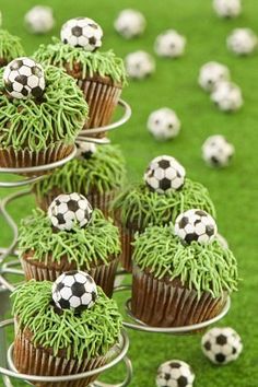 cupcakes decorated with grass and soccer balls are on display in the middle of a field