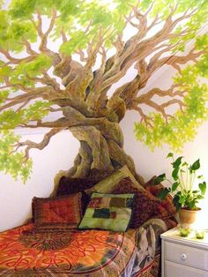 a bedroom with a large tree painted on the wall and bed in front of it