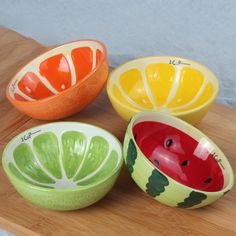 four bowls with different designs on them sitting on a wooden table next to each other