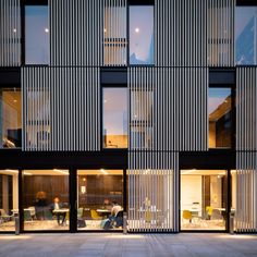 an office building with many windows and people walking in the doorways on either side