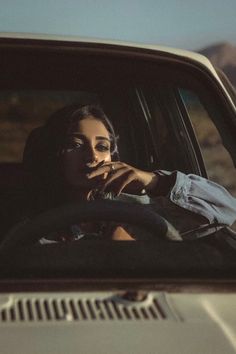 a woman sitting in the passenger seat of a car with her hand on her lips