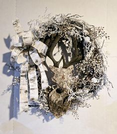 a deer's head made out of branches and ribbons on a white wall with shadows