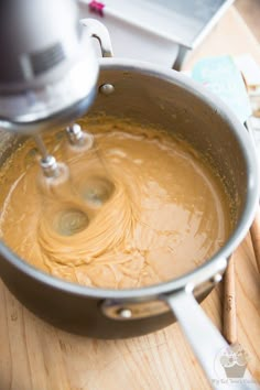 a mixing bowl filled with batter on top of a wooden counter next to a mixer