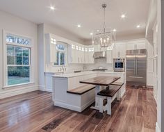 a large kitchen with white cabinets and wood flooring on the walls, along with a breakfast nook