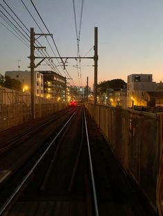 the train tracks are running parallel to each other at night, with buildings in the background